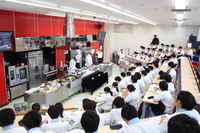 プロの講師陣が目の前で技術を実演。学生たちは真剣な表情でメモを取りながら、実践的なスキルを学んでいます。